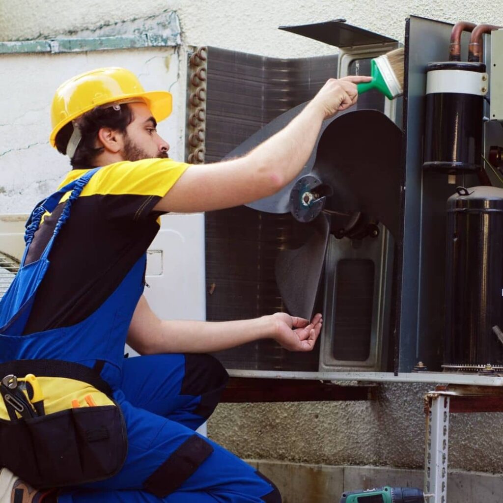 HVAC technician cleaning the blower fan of an air conditioning unit in Doha, Qatar